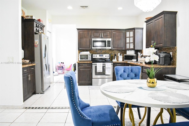 kitchen with dark brown cabinets, decorative backsplash, stainless steel appliances, and light tile patterned floors