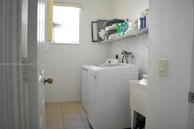 clothes washing area with light tile patterned floors, washer and clothes dryer, and sink