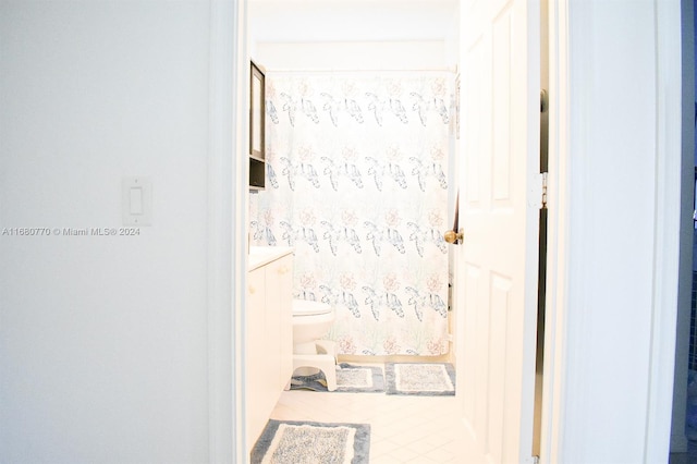 interior space with a shower with shower curtain, vanity, and toilet