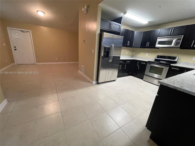 kitchen featuring light stone counters, stainless steel appliances, and light tile patterned floors