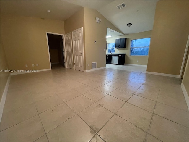 unfurnished living room featuring light tile patterned flooring, sink, and vaulted ceiling