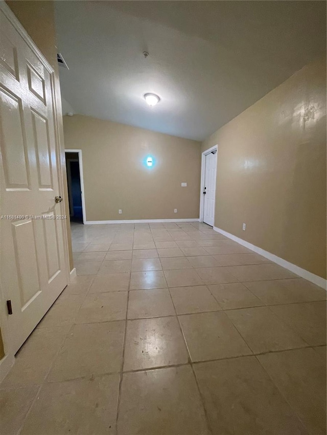 unfurnished room with vaulted ceiling and light tile patterned floors