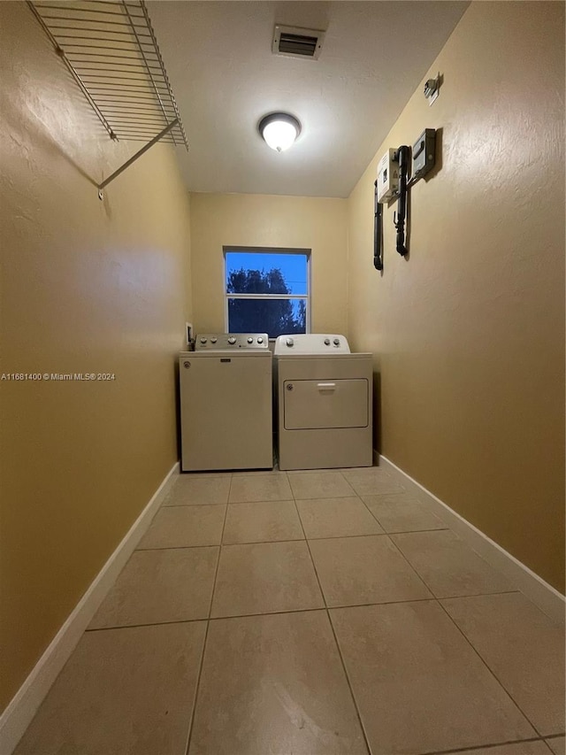 laundry area with independent washer and dryer and light tile patterned floors