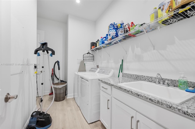 laundry area featuring cabinets, light hardwood / wood-style floors, sink, and independent washer and dryer