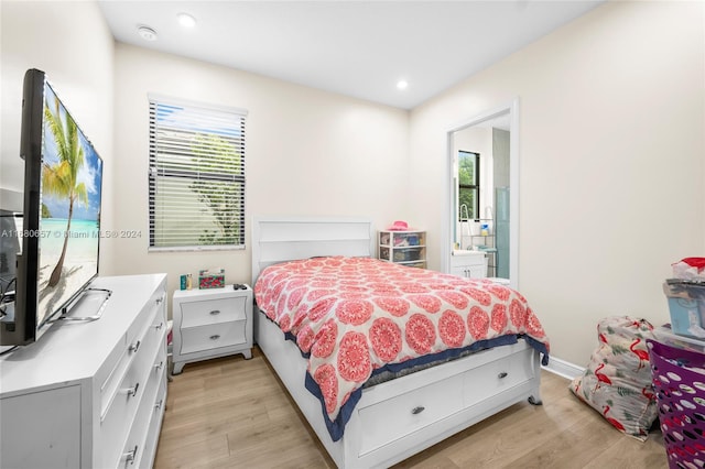 bedroom with light hardwood / wood-style floors, multiple windows, and ensuite bathroom