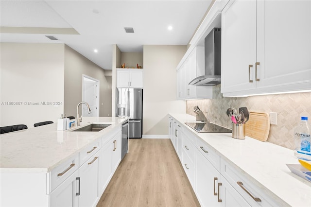 kitchen with stainless steel appliances, sink, wall chimney exhaust hood, white cabinets, and light wood-type flooring