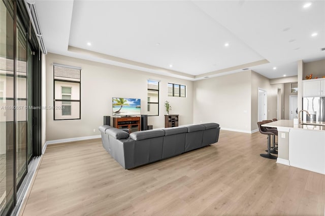 living room featuring a raised ceiling and light wood-type flooring