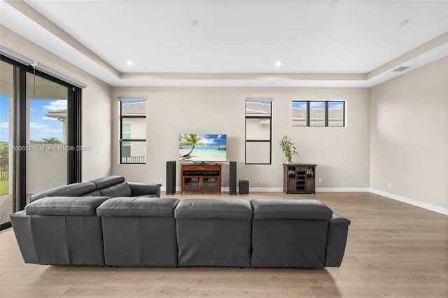 living room featuring light wood-type flooring and a tray ceiling