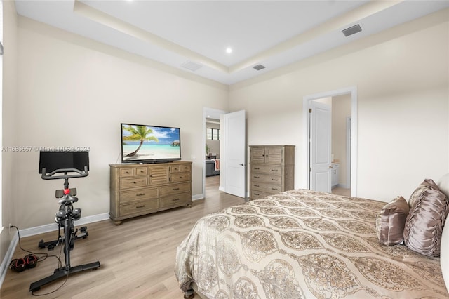 bedroom with a raised ceiling and light hardwood / wood-style flooring