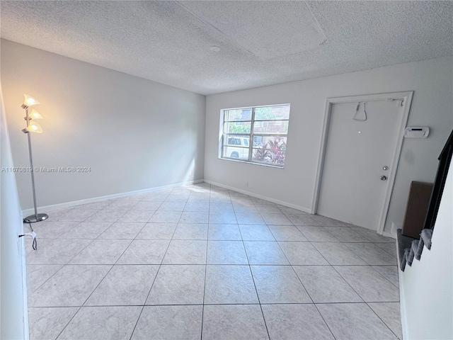 empty room featuring a textured ceiling and light tile patterned floors