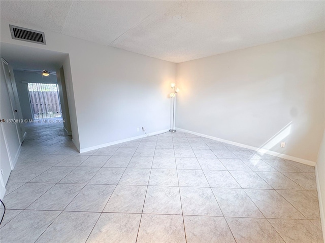 spare room featuring a textured ceiling and light tile patterned flooring