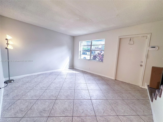 unfurnished room with a textured ceiling and light tile patterned floors