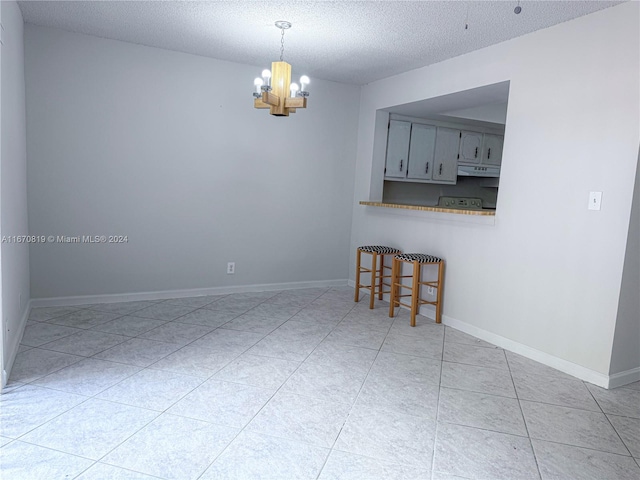 unfurnished dining area featuring an inviting chandelier, a textured ceiling, and light tile patterned floors