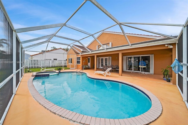 view of pool with french doors, a pool with connected hot tub, a patio area, fence, and a lanai