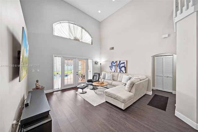 living area with a high ceiling, dark wood-style flooring, visible vents, baseboards, and french doors