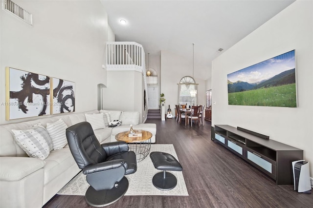 living area with a towering ceiling, visible vents, and dark wood-type flooring