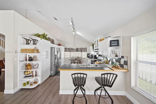 kitchen with stainless steel appliances, a breakfast bar, a peninsula, and tile counters