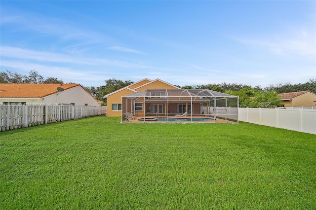 rear view of property featuring glass enclosure, a yard, a fenced backyard, and a fenced in pool