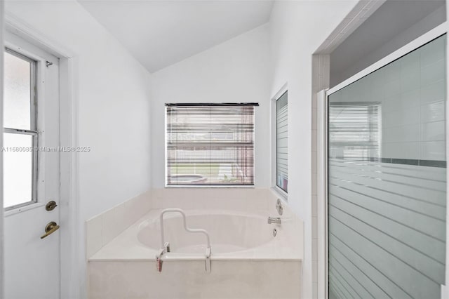 bathroom with lofted ceiling, a stall shower, and a bath