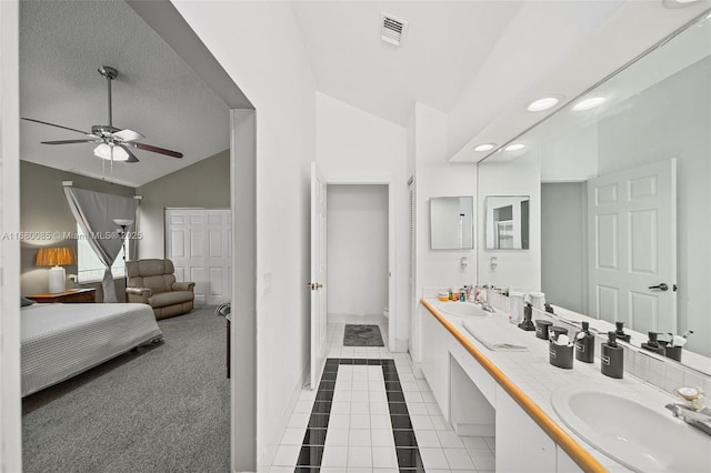 bathroom featuring lofted ceiling, a sink, visible vents, tile patterned floors, and double vanity