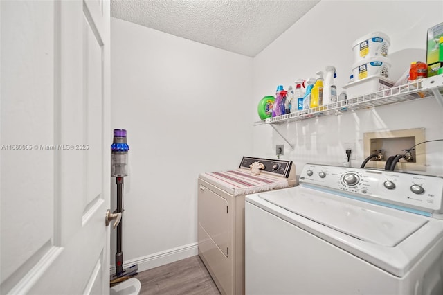 laundry area with a textured ceiling, wood finished floors, washer and dryer, laundry area, and baseboards