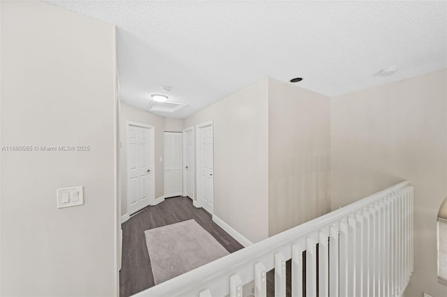 hall with a textured ceiling, dark wood finished floors, and baseboards