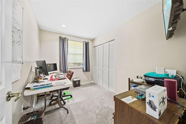 office area featuring light carpet, baseboards, and a textured ceiling