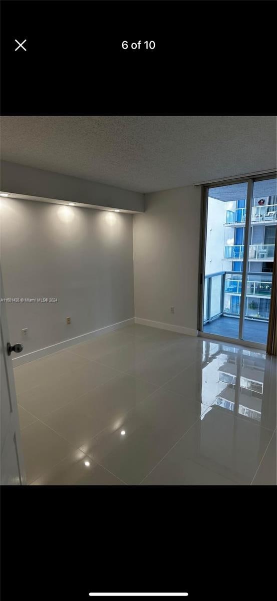 tiled empty room with a textured ceiling and a wall of windows