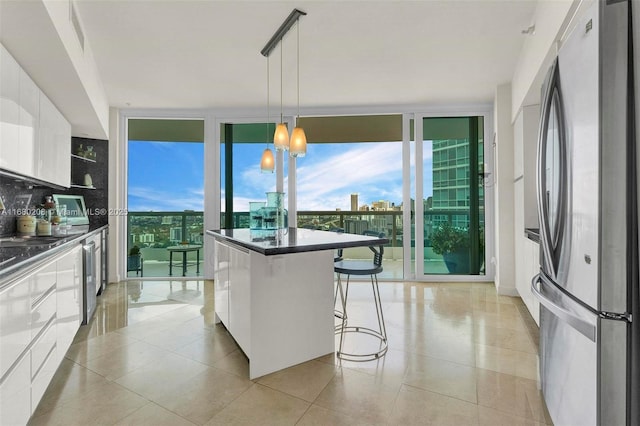 kitchen featuring stainless steel appliances, white cabinets, a wall of windows, dark countertops, and modern cabinets