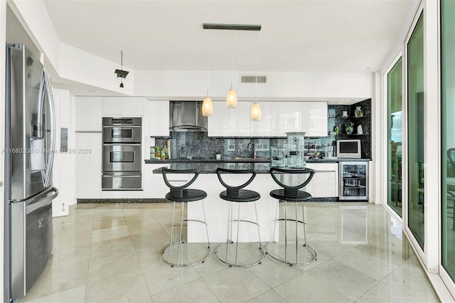 kitchen featuring wine cooler, a warming drawer, visible vents, appliances with stainless steel finishes, and wall chimney exhaust hood