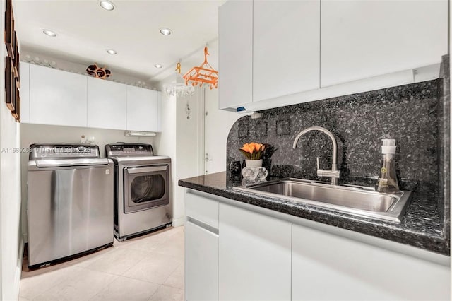 kitchen featuring light tile patterned flooring, a sink, white cabinetry, decorative backsplash, and washing machine and clothes dryer