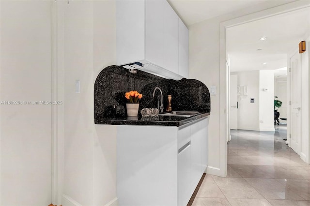 kitchen featuring dark countertops, modern cabinets, a sink, white cabinetry, and backsplash