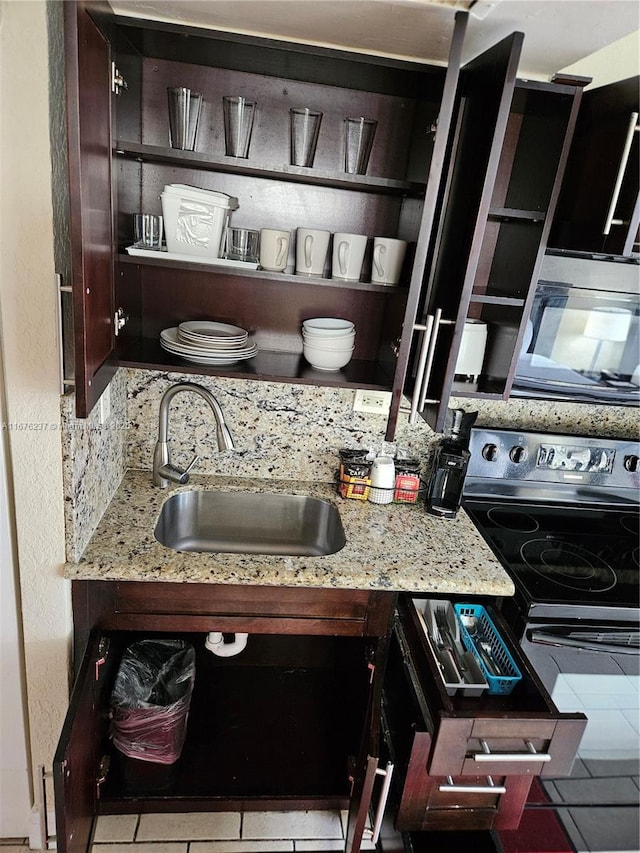 kitchen with open shelves, electric range, a sink, and light stone counters