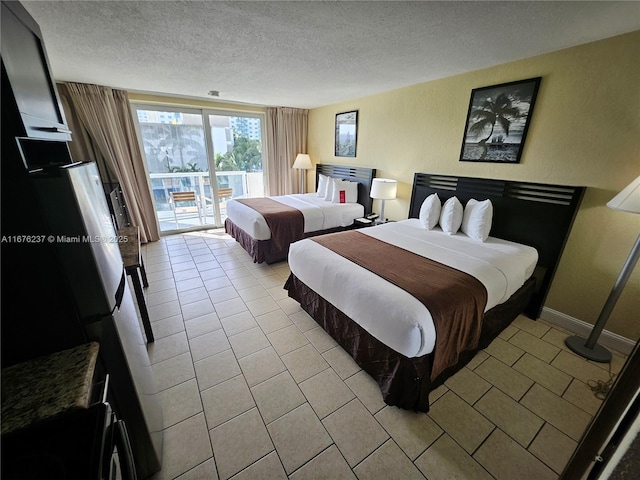 bedroom featuring a textured ceiling, light tile patterned flooring, baseboards, and access to exterior