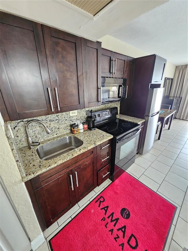 kitchen with black appliances, tasteful backsplash, light tile patterned floors, and a sink