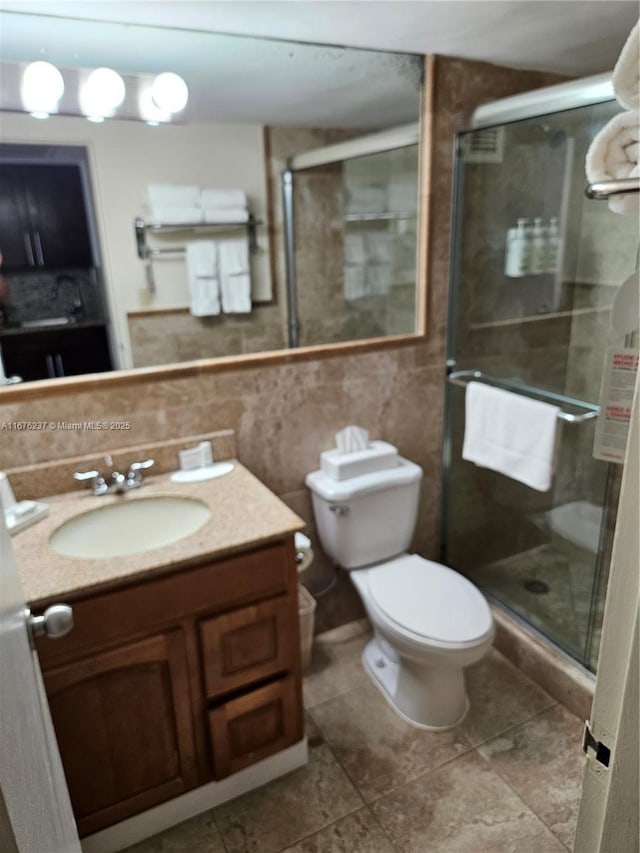 bathroom featuring a stall shower, tile walls, vanity, and toilet