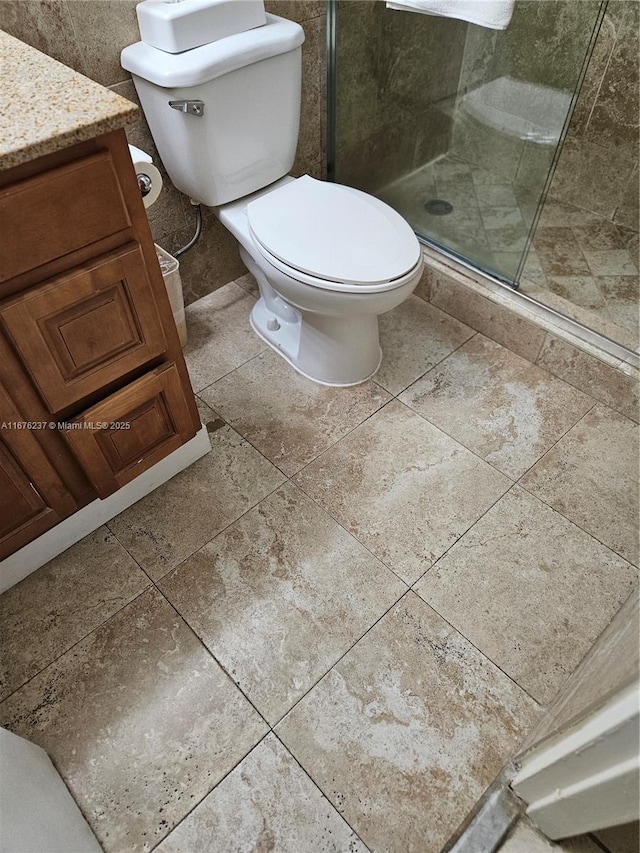 bathroom with toilet, a stall shower, and vanity