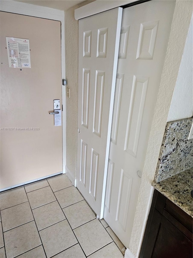 hallway with a textured wall and light tile patterned flooring