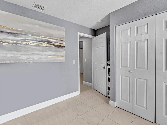 foyer entrance with a textured ceiling and light tile patterned floors