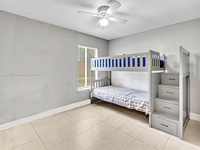 bedroom featuring a textured ceiling, light tile patterned floors, and ceiling fan