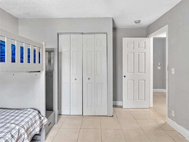 bedroom with light tile patterned flooring, a textured ceiling, and a closet