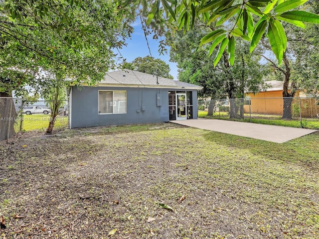 back of house with a patio and a lawn