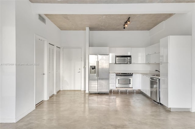 kitchen featuring white cabinetry, a towering ceiling, appliances with stainless steel finishes, and sink