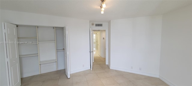 unfurnished bedroom with a closet, a textured ceiling, and light tile patterned floors