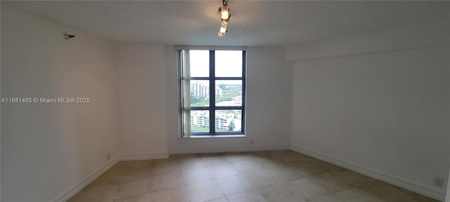 unfurnished room featuring a textured ceiling and light tile patterned floors