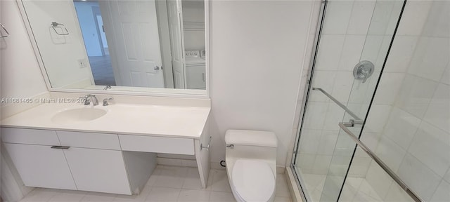 bathroom featuring washer / dryer, tile patterned flooring, vanity, an enclosed shower, and toilet