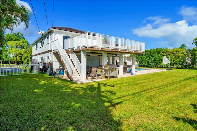 back of property with a swimming pool side deck, a patio area, and a lawn