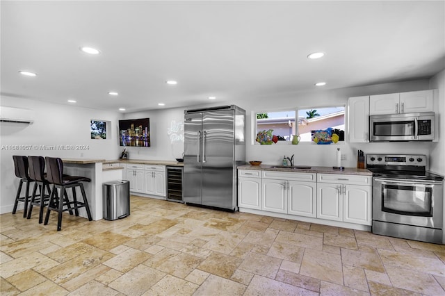 kitchen featuring appliances with stainless steel finishes, a kitchen bar, white cabinets, and beverage cooler