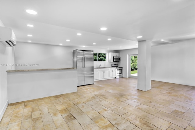 kitchen with a wall mounted AC, sink, white cabinets, and stainless steel appliances