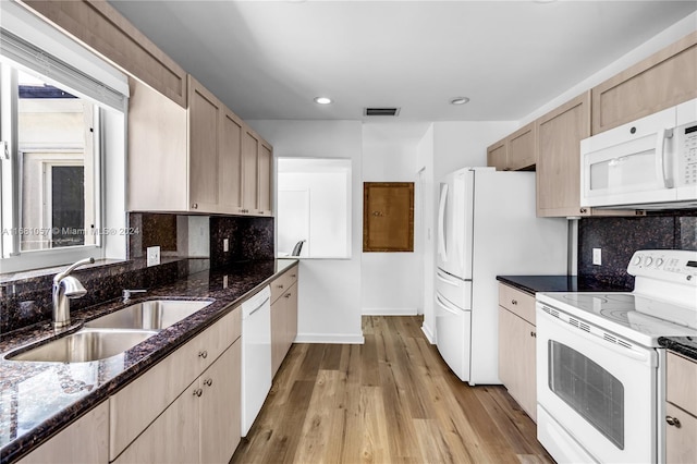 kitchen featuring dark stone counters, sink, light wood-type flooring, and white appliances